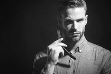 Barbershop. Stylish unshaven man with straight razor. Barber shop, hairdresser, shaving beard. Straight razor, barber. Beard man, bearded male. Copy space for advertising barber shop. Black and white.