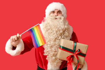 Santa Claus with LGBT flag and Christmas gift on red background