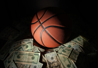 A basketball on a pile of money on dark background