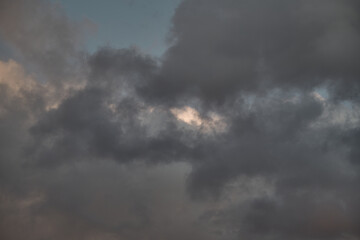 Gray cumulus clouds illuminated by the setting sun in a close-up shot, shadows on the clouds in the sky before twilight.