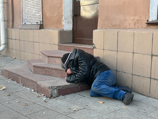 Homeless dirty person lying on the ground in Moscow, Russia