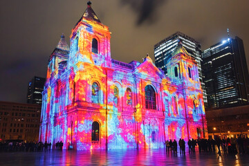 Spectators looking at the colorful light projections illuminating montreal's mary queen of the world cathedral during the aura festival