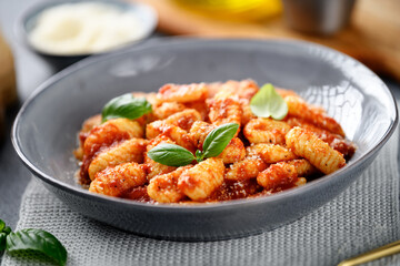 Traditional Italian potato gnocchi with tomato sauce, parmesan cheese and fresh basil leaves