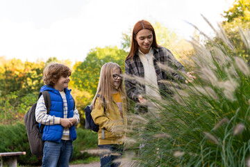 Naklejka premium Schoolchildren with teacher exploring meadow on sunny day engaging in hands-on biology lessons