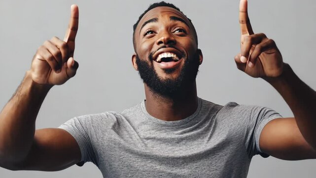 Black man with a gentle smile, wearing a gray shirt and pointing upwards as if showing something interesting, on a plain background