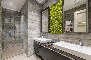 Modern bathroom, decorated with light gray tiles. Original natural moss wall decoration with mirrors.