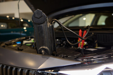 Closeup photo of black car battery connected with jumper cables for repair or recharging