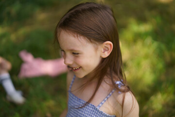 Cute girl in a sundress on the lawn close-up. Concept of children's health, travel, fun