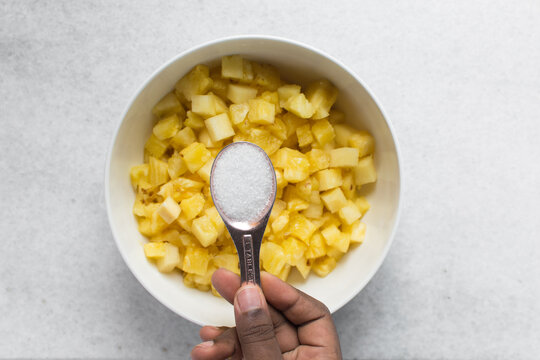 A tablespoon of white sugar, granulated sugar in a rose-gold spoon