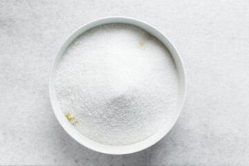 Overhead view of diced pineapple and sugar being mixed together in a white bowl, process of making pineapple cheong or pineapple syrup