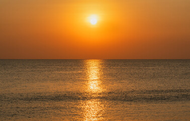 Calm sea surface with a golden sunset on the horizon