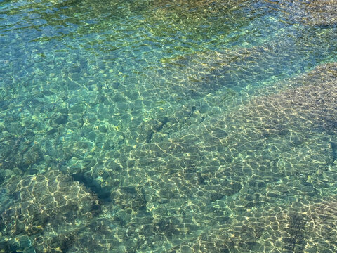 Sea transparent emerald water with stones at the bottom.