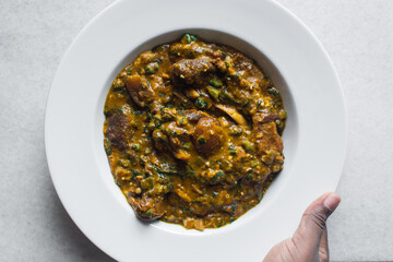 Overhead view of nigerian ogbono soup in a white plate, top view of ogbono draw soup with assorted meats in a soup plate, flatlay of nigerian ogbono and okra soup