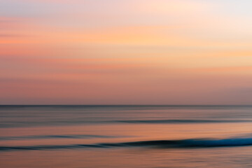 Serene horizon with gentle waves under a warm, fading sky.