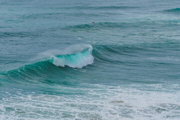 Turquoise waves cresting and frothing in a rhythmic pattern at Nazare's renowned surf spot.