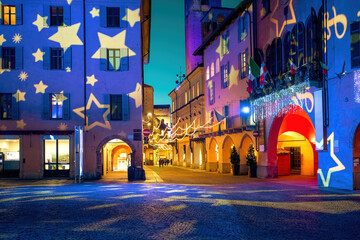 Old town square in the evening illuminated and decorated for Christmas holidays in Italy.