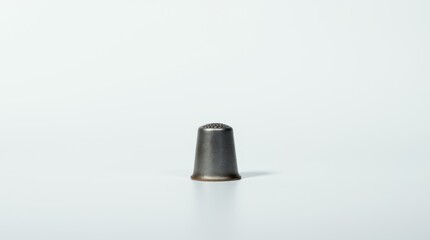 Small Metallic Sewing Thimble with Subtle Wear and Tear on White Background