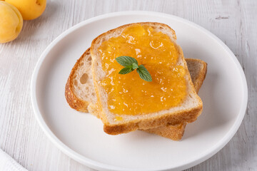 Toasts with tasty apricot jam on a white wooden table