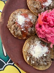 Traditional garnachas served on a clay plate at a restaurant in Oaxaca, Mexico. Deep-fried beef on masa with salsa and cheese. Top View.