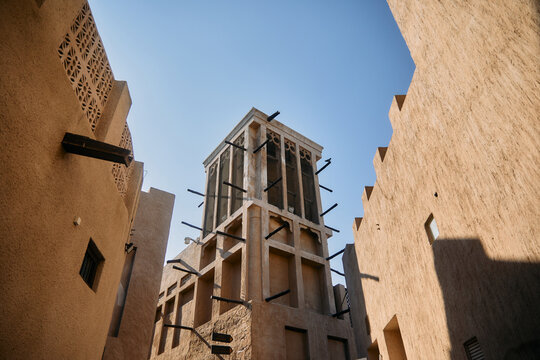 A view of a traditional wind tower in Dubai surrounded by historic beige facades, showcasing Middle Eastern architectural ingenuity and heritage