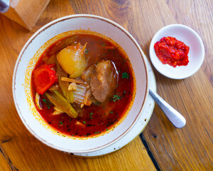 Oriental Lagman soup with lamb and vegetables on a wooden table in a restaurant