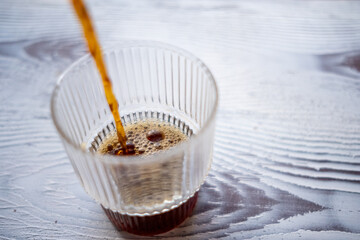 coffee being poured into a glass cup on a white background in slow motion