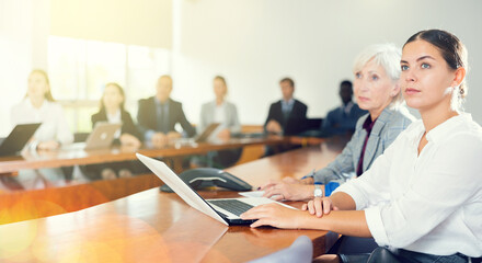 Group of corporate employees attentively listening to business presentation in conference room