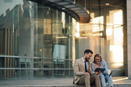 Business people having fun working together using tablet computer outside office building