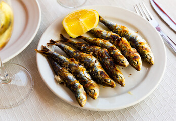 Malaga traditional fried on skewers sardines on plate on wooden table