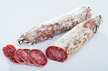Image of spanish longaniza salami sausages cut in slices on a white surface, close-up