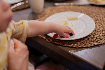 Small baby toddler boy arm reaching for plate to pick up snacks and eat during launch with parents