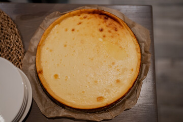 Magnificent top view of tasty home made cheesecake  with round crust in natural table with plates on the side