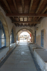 A tranquil corridor leads to a sunlit courtyard in a historic building during the afternoon.
