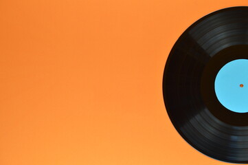 old black vinyl record with blank cyan label half on orange background