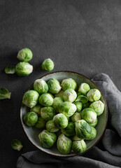 Fresh brussels sprouts in a bowl on a dark background with napkin. Vegetarian healthy food concept