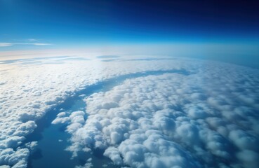 Naklejka premium Aerial view of Earth from high altitude with blue sky and white clouds. View from airplane window over landscape. Flight travel, tourism, nature and weather themes.