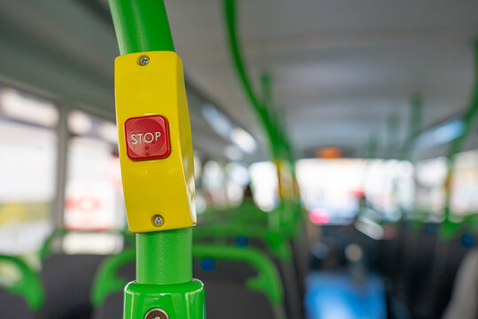 red stop button wrapped in yellow casing and green pole on a bus in London