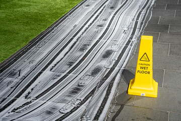 Wet floor danger sign or information element with detergent marks on tiled floor.