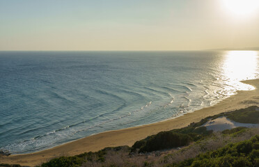 A tranquil sunset over a serene beach with gentle waves lapping at the golden shoreline.