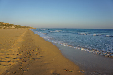 Golden sands stretch along a tranquil coastline at sunset near a peaceful beach.