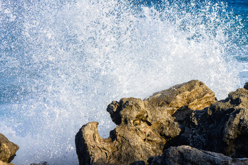 Waves crashing against rugged coastal rocks at sunset in a serene seaside escape.