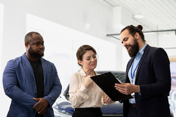 Salesman talking with customers, showcasing dealership vehicles and explaining their features...