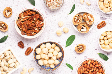 Assortment of fresh dry nuts and seeds on light marble background top view. healthy vegan food concept.
