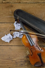 old broken violin on rural wooden floor with antique violin case and tattered fiddlestick