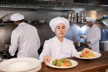 Female chef puts ready meals on shelves in restaurant