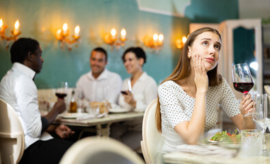 Elegant upset woman is expecting man for dinner in luxury restaurante