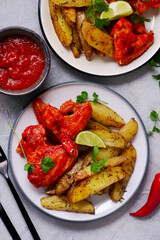 Chicken wings with spicy mango habanero sauce, lime wedges and cilantro .selective focus