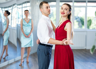 Man and girl take dance lessons from experienced teacher. Couple in stage costumes practices waltz...