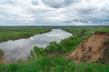 A serene river flowing through lush greenery under a cloudy sky