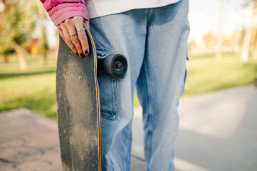 Skater holding skateboard in skatepark on sunny day